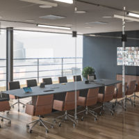 Upscale conference room with highly polished round table and executive chairs overlooking a sunrise through a wall of windows.