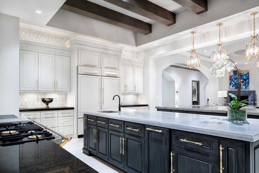 A kitchen with white marble countertops, pendant lights, and recessed ceiling lights.