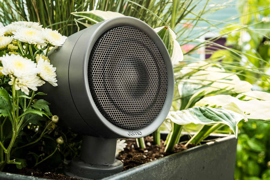 A closeup of a Klipsch outdoor speaker in a planter box outdoors.