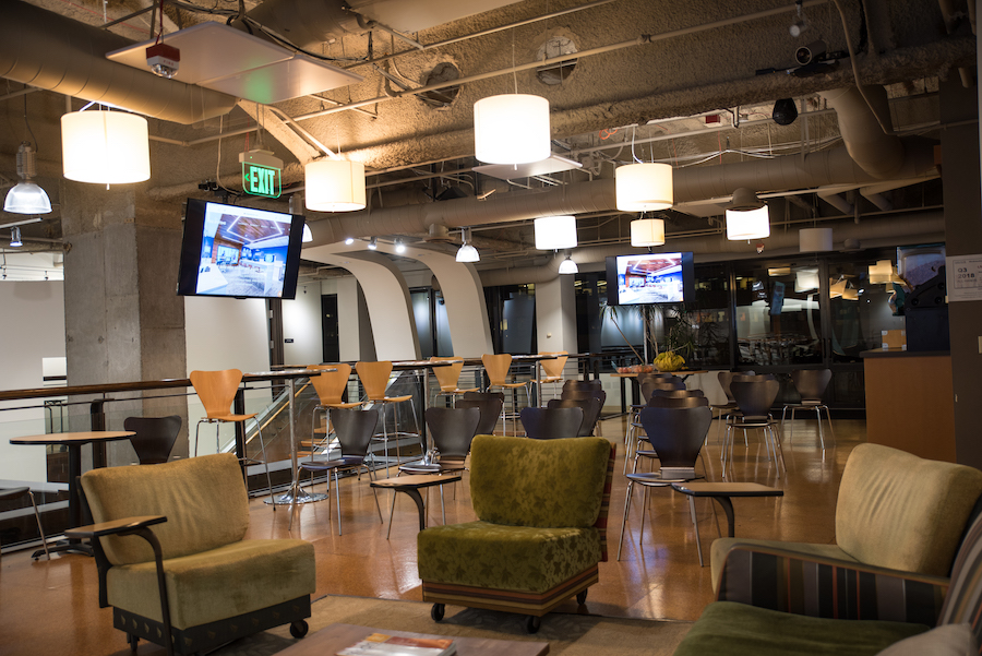 A common area lounge in a corporate setting with multiple video monitors.