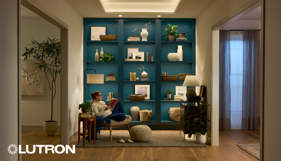 A woman in a cozy reading nook with Lutron lighting highlighting teal bookshelves and decorative accents for a warm, inviting atmosphere.